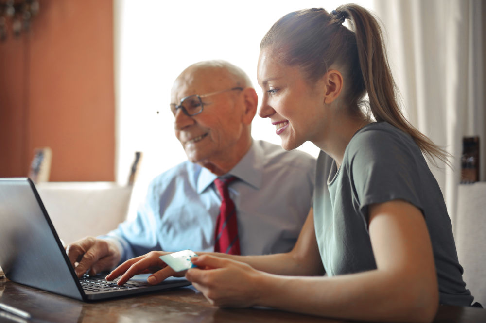 Woman Assisting Elderly Man on the Computer